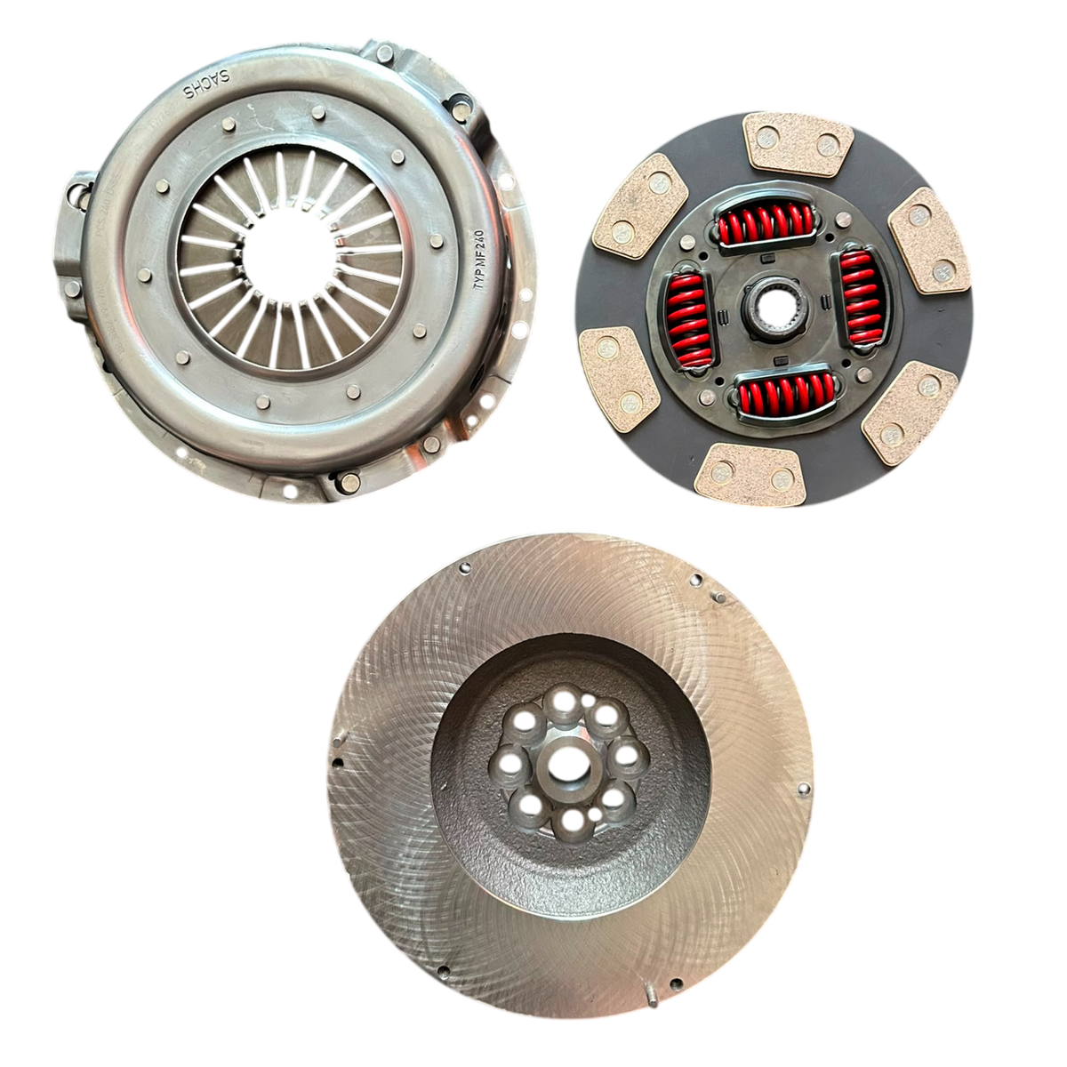 Three automotive clutch components photographed on a plain white background: a pressure plate on the upper left, a flywheel on the lower center, and a release bearing assembly on the upper right.