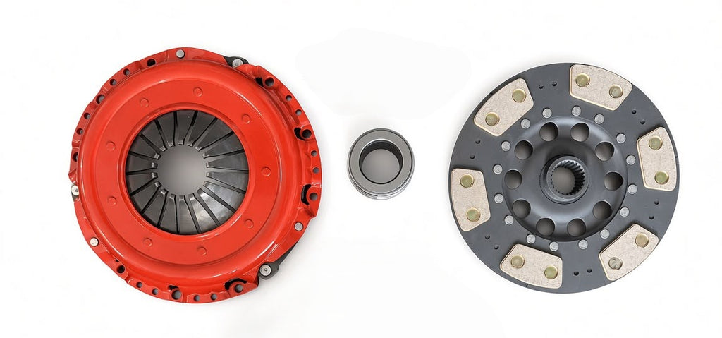 A clutch assembly consisting of a bright red pressure plate, a dark gray clutch disc with beige friction plates, and a small silver steel bearing, displayed on a clean white background.